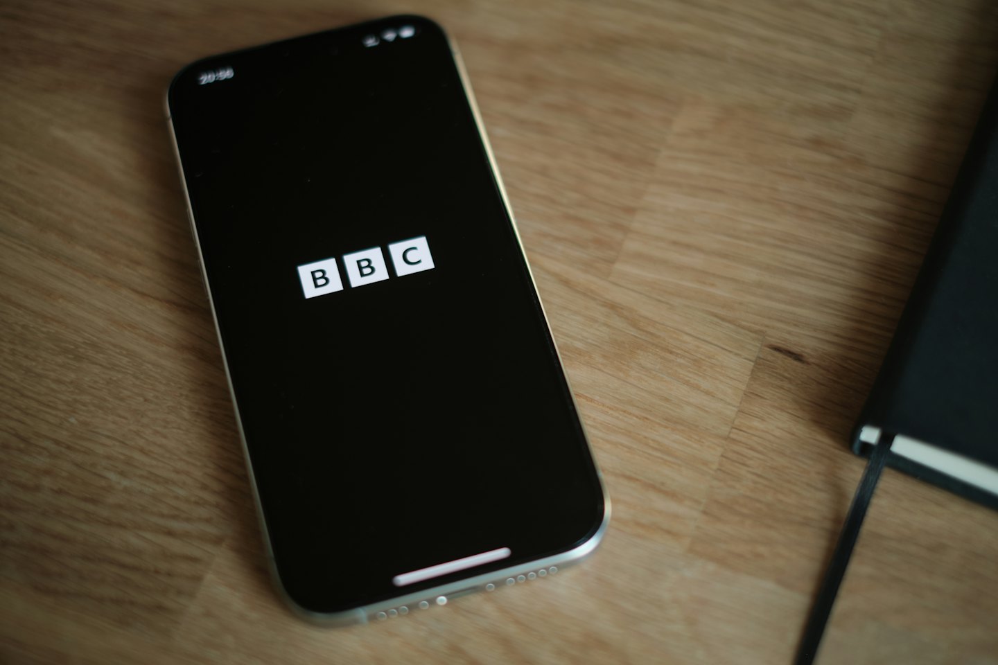 Smartphone displays the BBC logo on a wooden table.