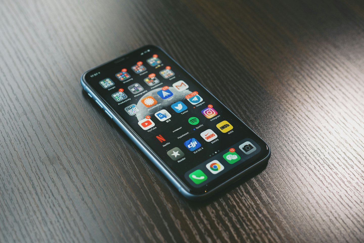 Modern smartphone resting on a dark wooden table.