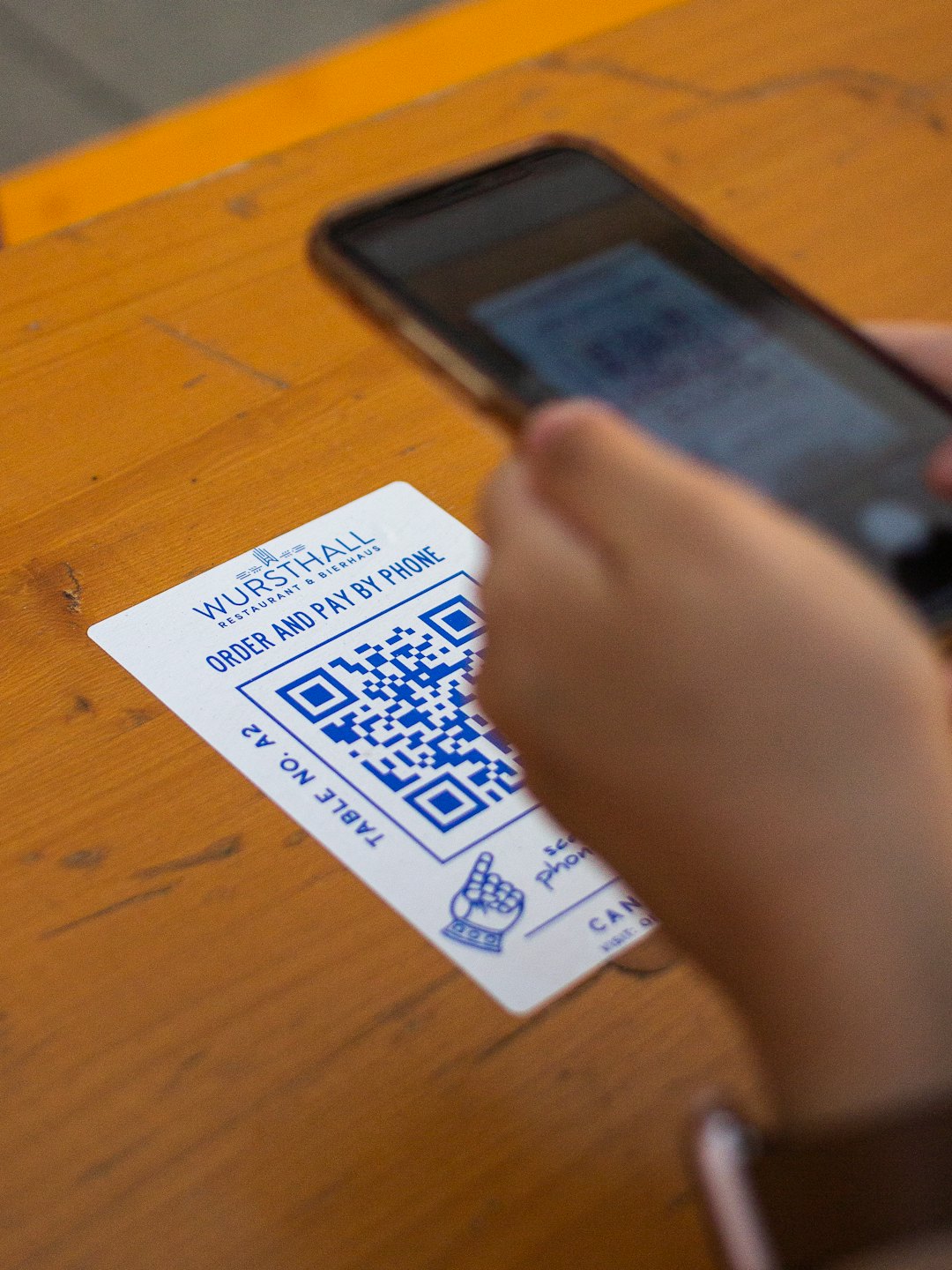 Hands holding phone to scan QR code on restaurant menu.