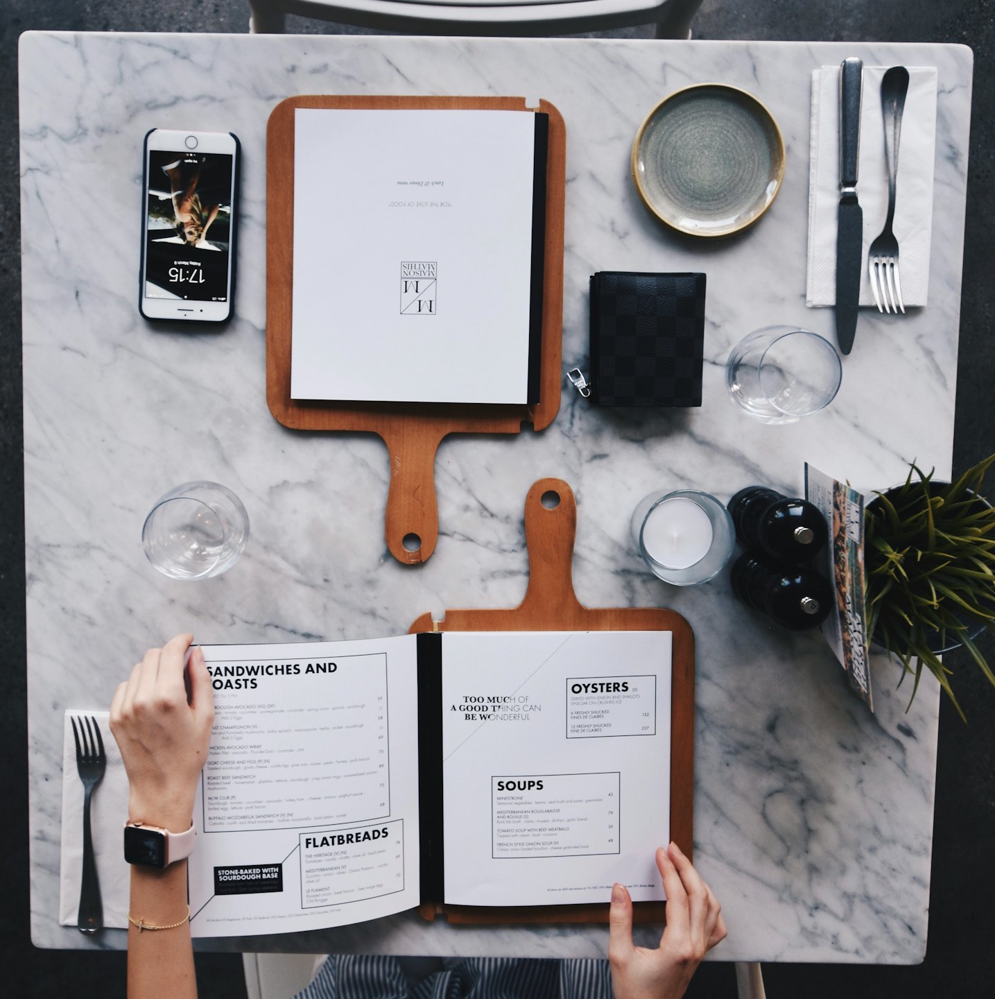 Hands holding an open restaurant menu at a marble table.